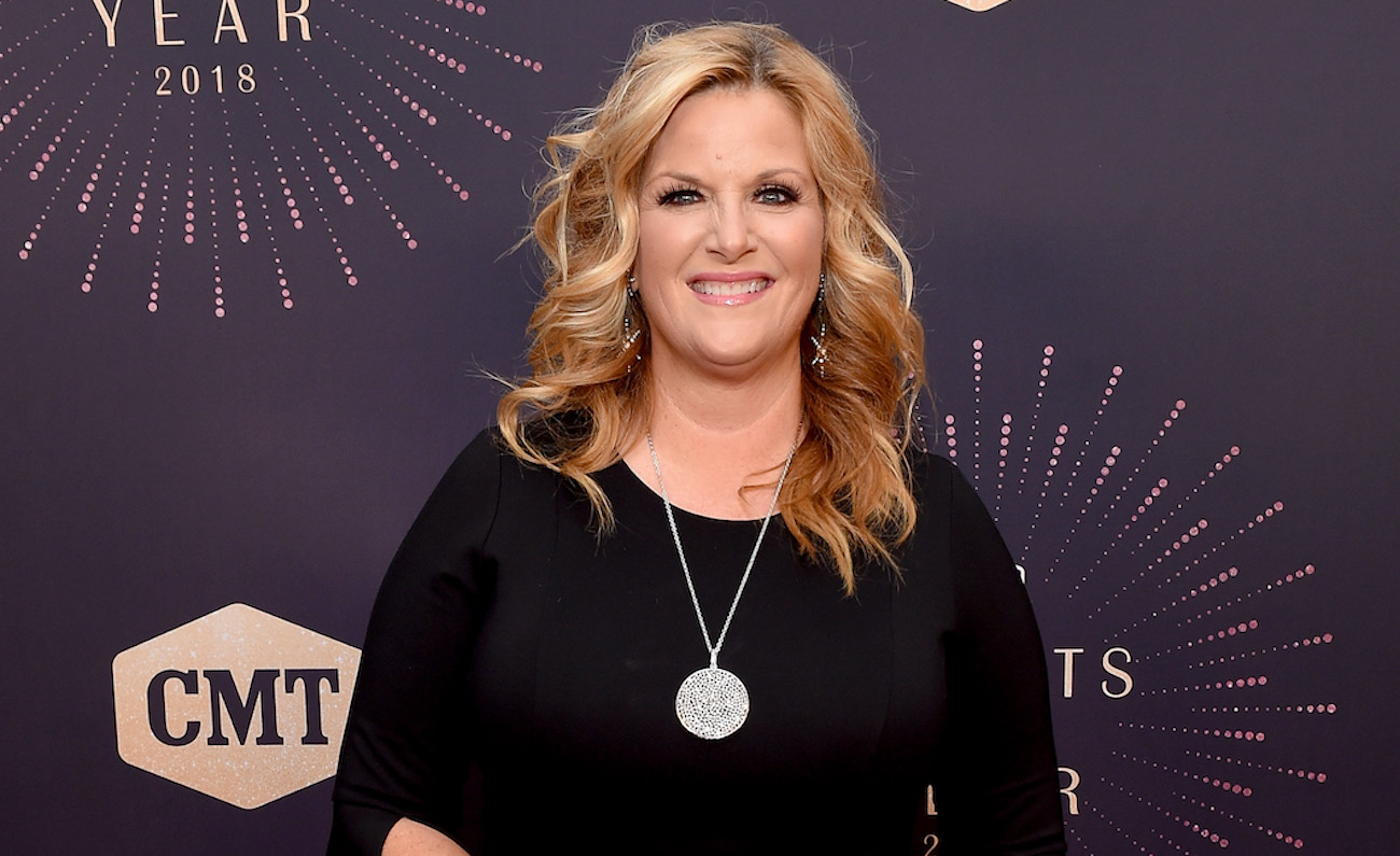 Trisha Yearwood sourit pour les caméras posant sur le tapis rouge dans une tenue noire