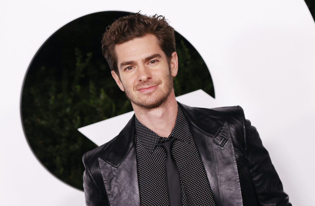 Andrew Garfield porte un costume noir et sourit sur le tapis rouge
