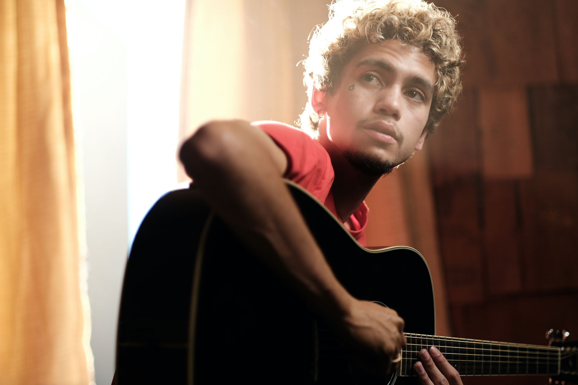 Dominic Fike dans le rôle d'Elliot tenant une guitare dans 