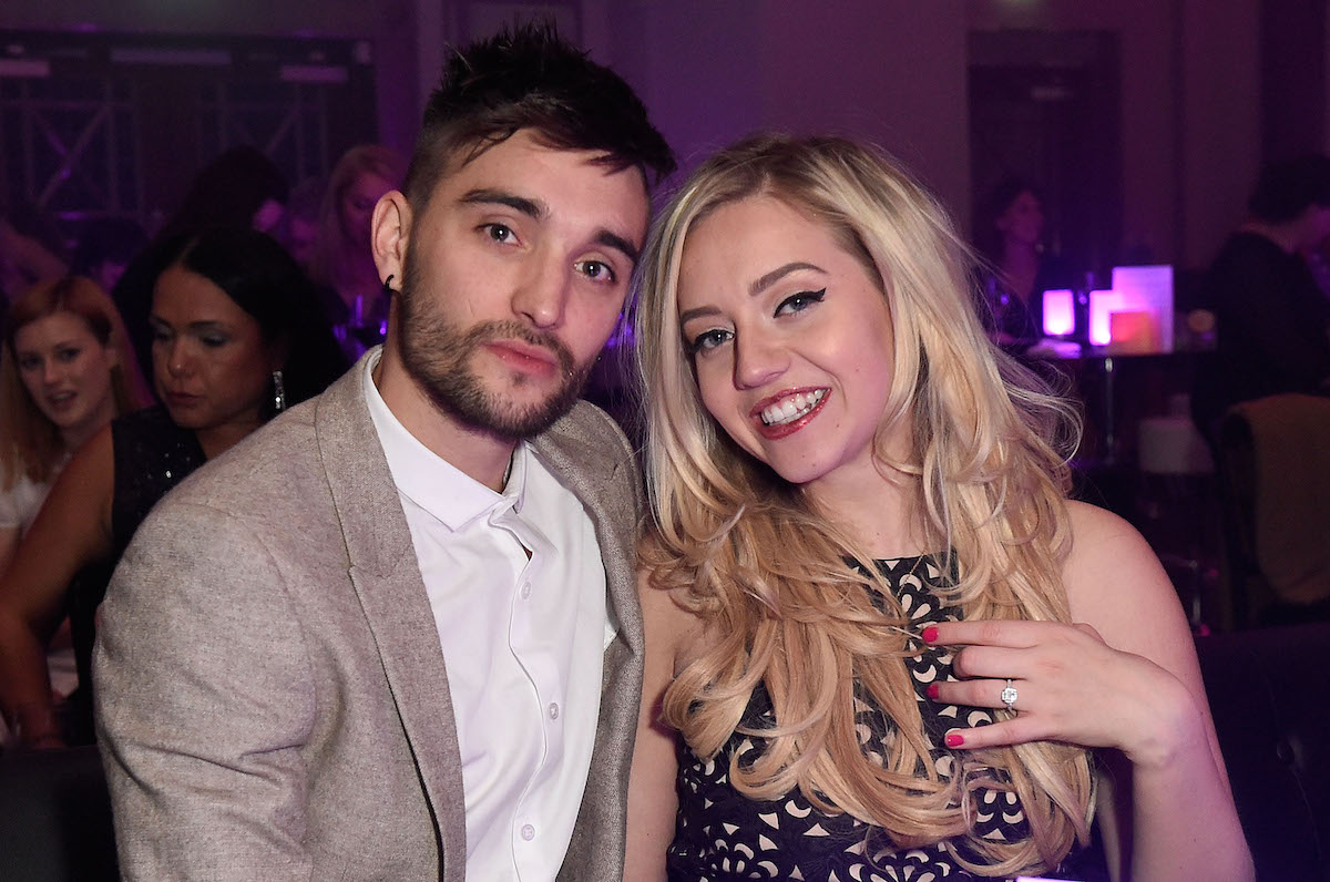 Tom Parker et Kelsey Parker de The Wanted sourient en s'asseyant l'un à côté de l'autre