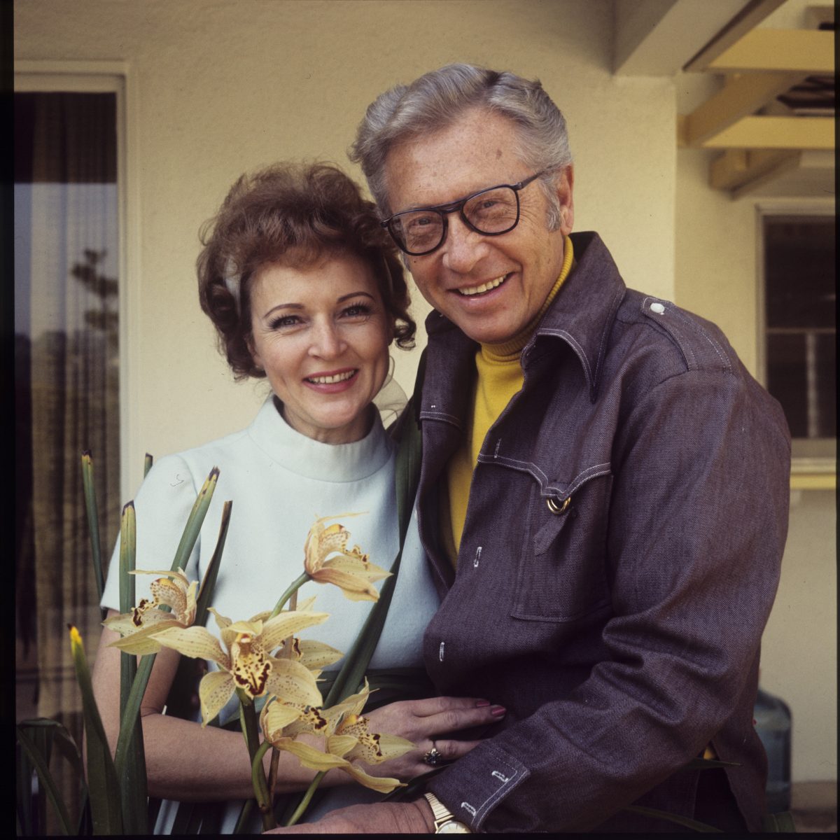 Betty White et Allen Ludden s'embrassent et sourient à l'extérieur de leur maison