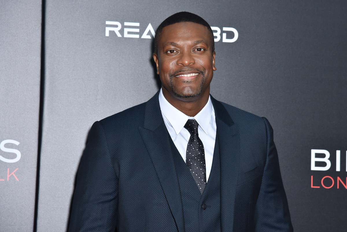 Chris Tucker porte un costume et sourit sur le tapis rouge