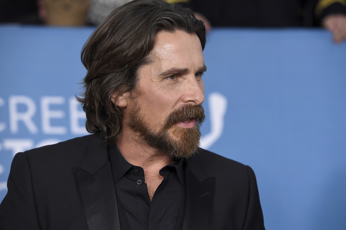 Christian Bale parle en portant un costume noir.