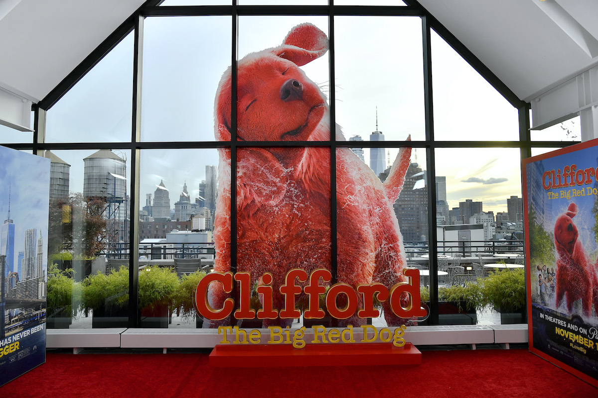 Un voyageur debout de Clifford le gros chien rouge est assis à l'extérieur d'une fenêtre au milieu d'un paysage urbain