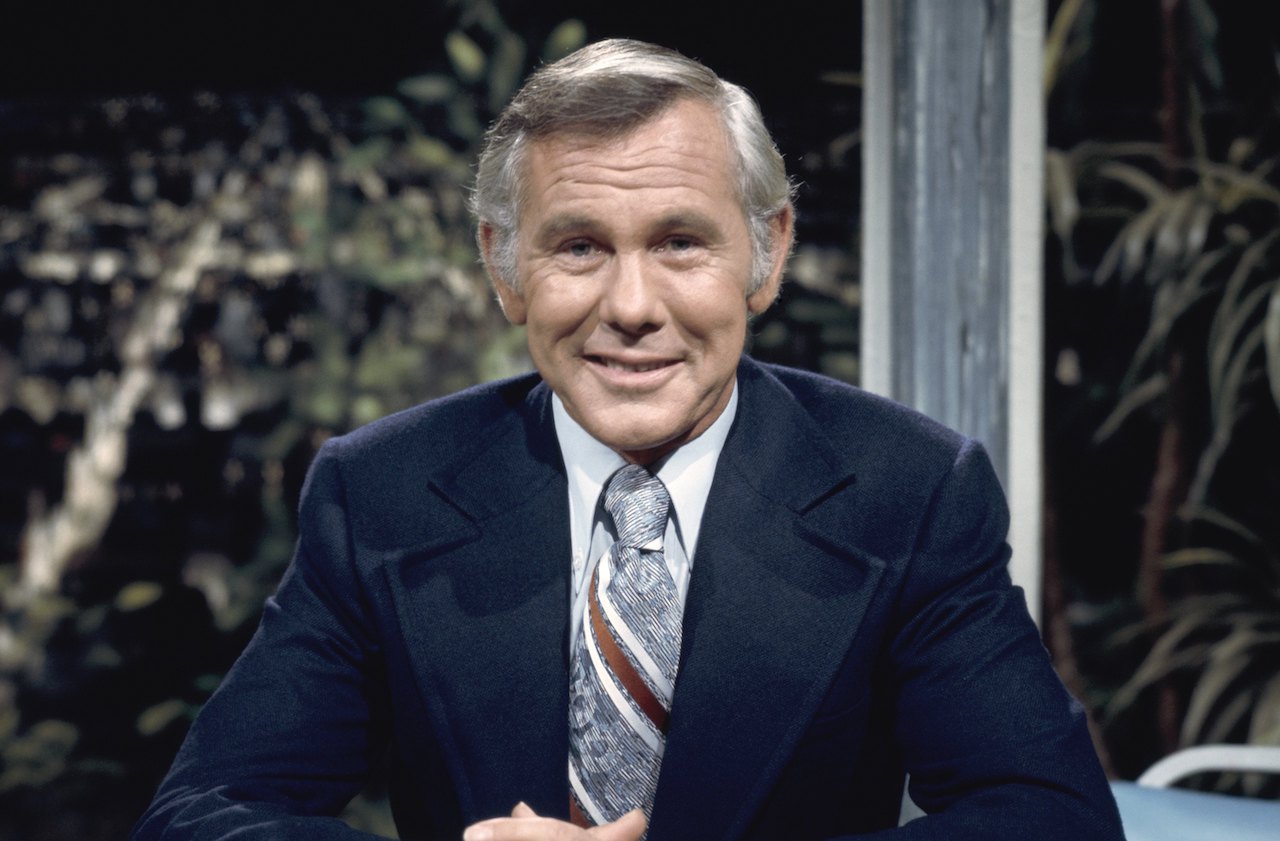 Johnny Carson dans une veste bleu marine, assis au bureau 'The Tonight Show'