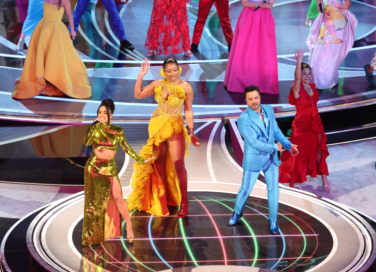 Becky G, Megan Thee Stallion et Luis Fonsi se tiennent sur scène portant des couleurs vives lors d'une représentation à la 94e cérémonie des Oscars à Hollywood, CA