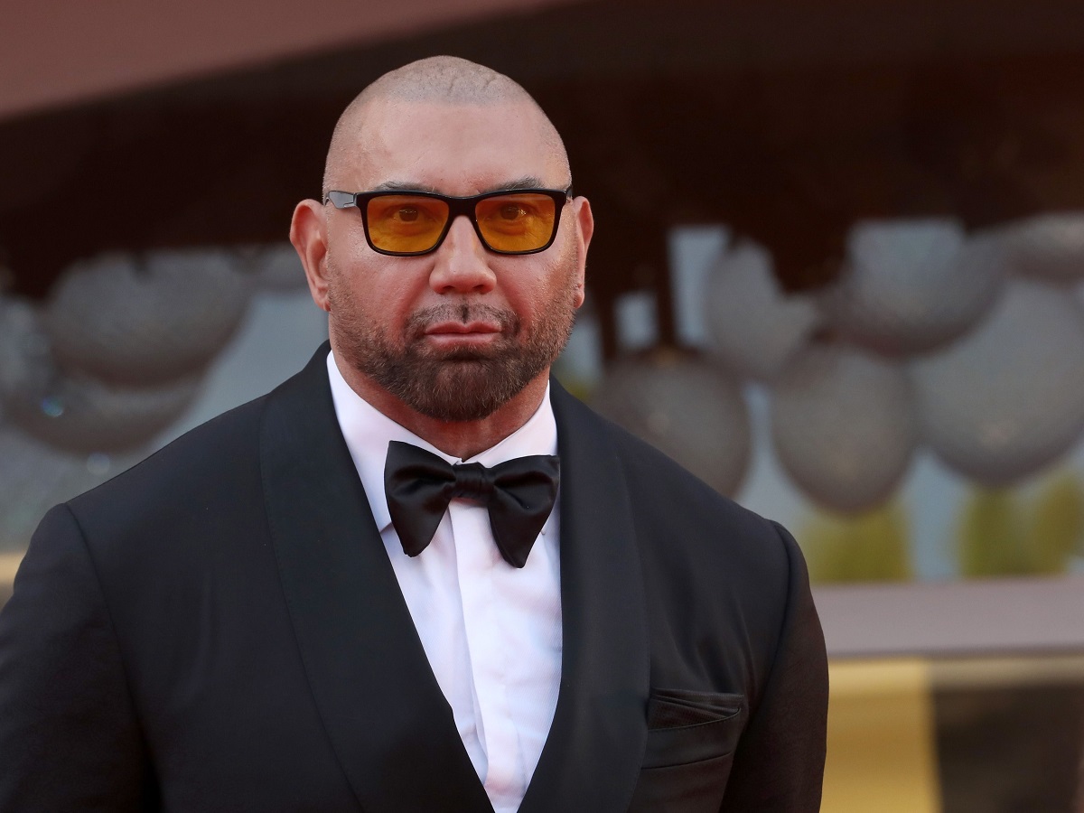 Dave Bautista sourit en portant des lunettes de soleil.