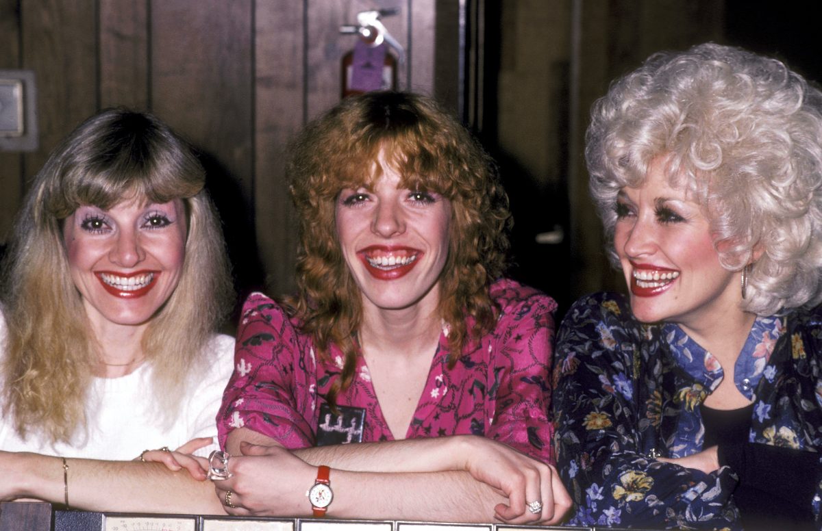 Dolly Parton et ses frères et sœurs Stella Parton et Freida Parton se tiennent souriants à la suite. 