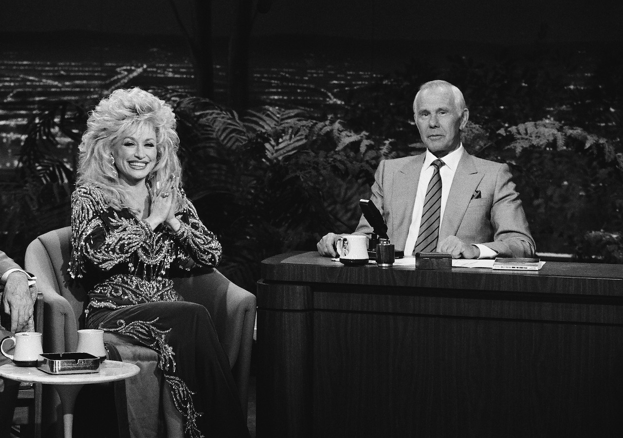 Photo en noir et blanc: Dolly Parton est assise, les mains jointes en forme de prière, à côté de Johnny Carson dans 