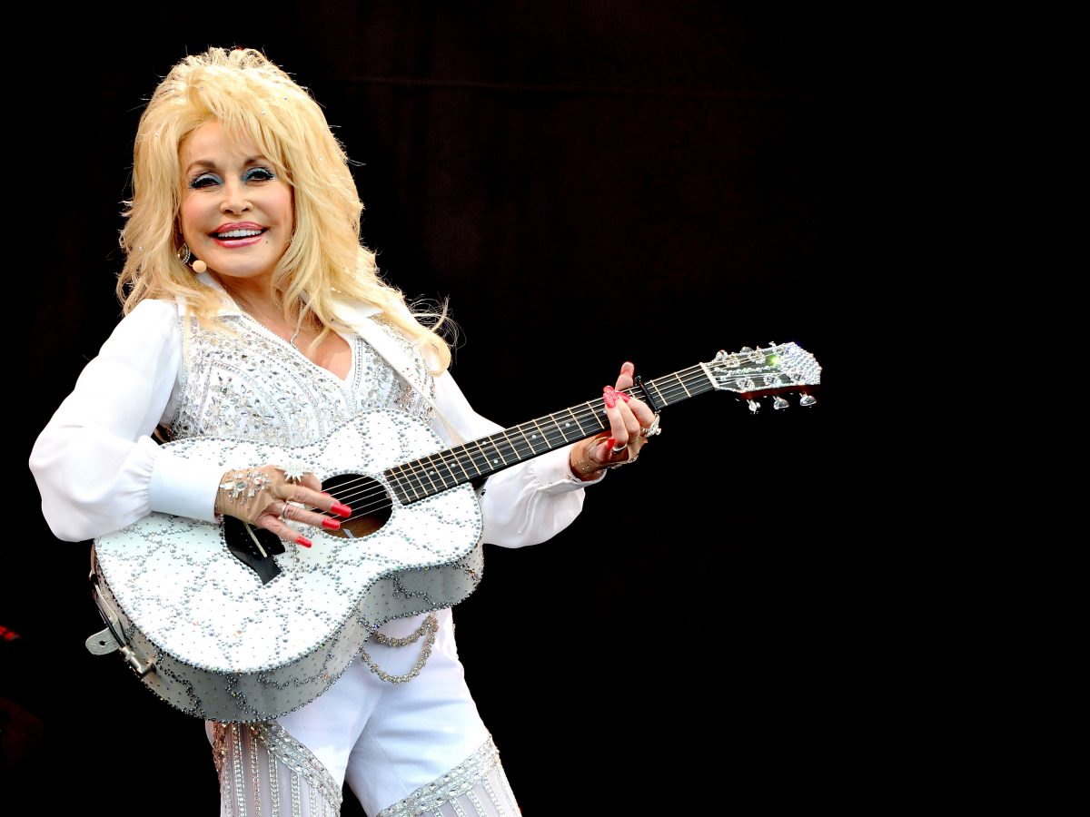 Dolly Parton pose avec une guitare blanche ornée de bijoux