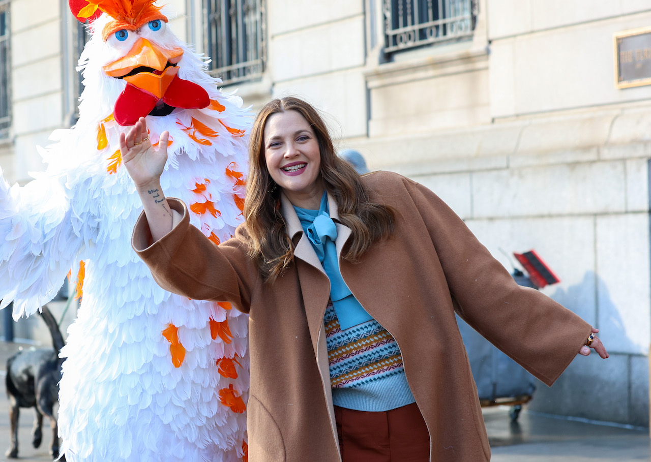 Drew Barrymore avec une personne en costume de poulet, agitant ensemble un taxi