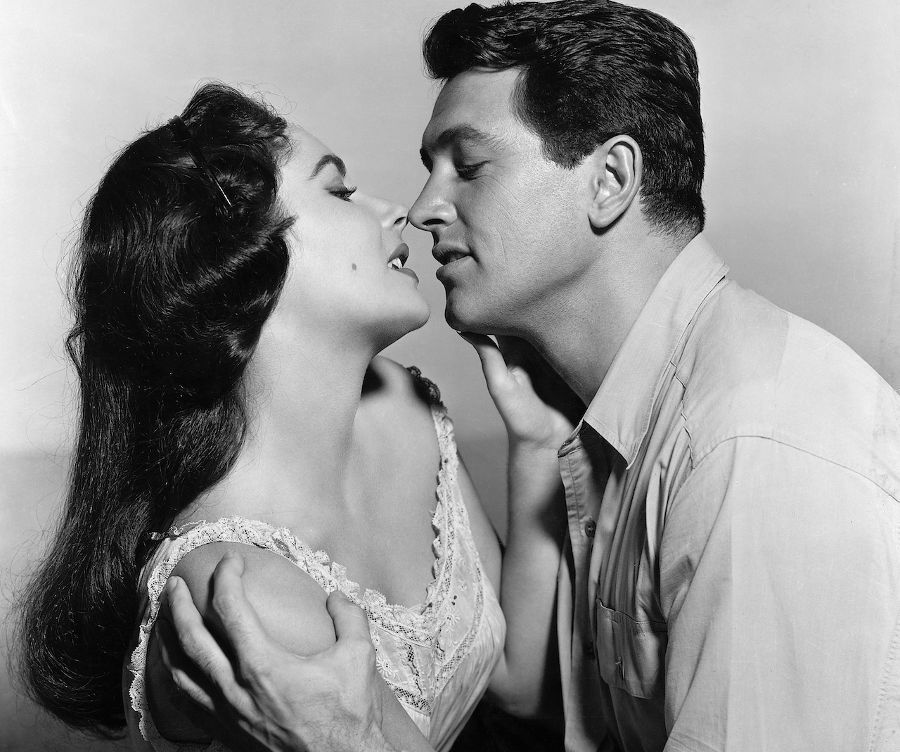 Elizabeth Taylor et Rock Hudson dans une scène du film de 1956, "Giant".  Ils sont représentés dans une vue à la taille, enlacés.
