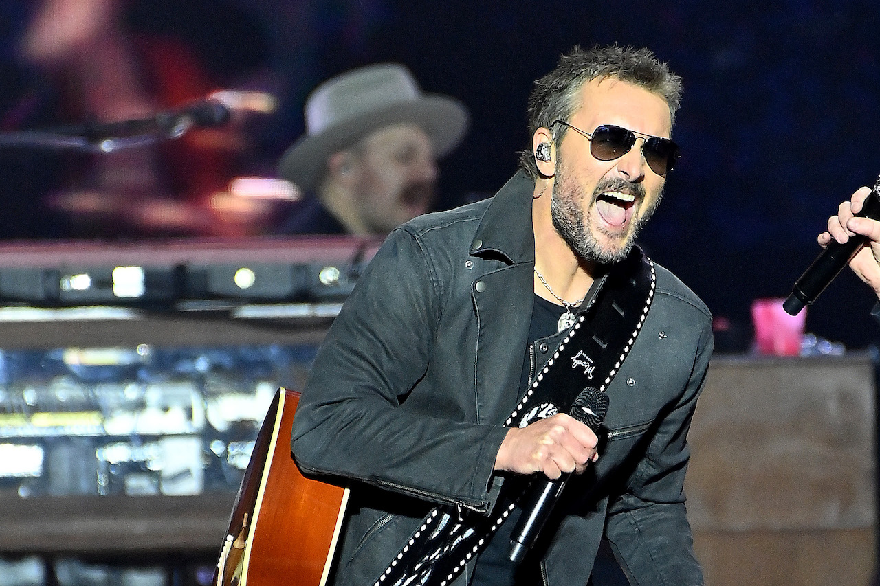 Eric Church portant des lunettes de soleil aviateur, tenant un microphone et se produisant sur scène