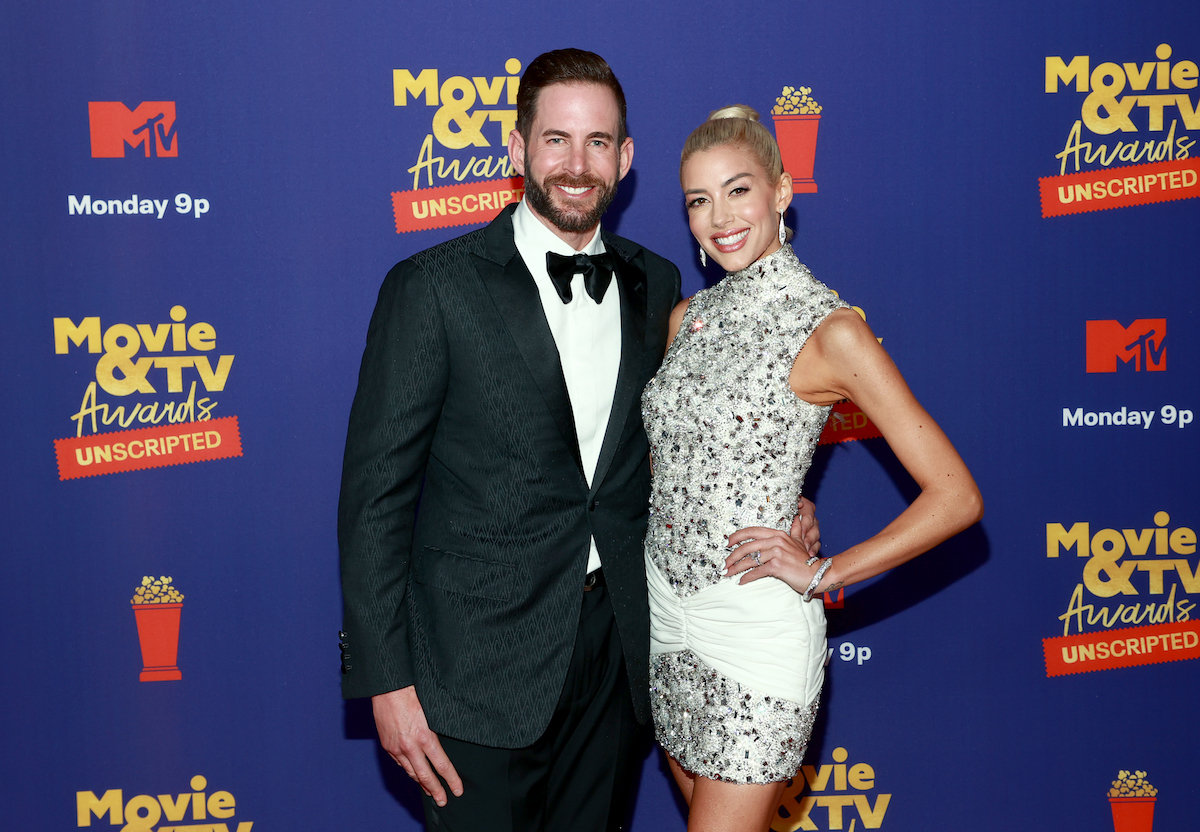 Tarek El Moussa et Heather Rae Young sourient et posent ensemble lors d'un événement.
