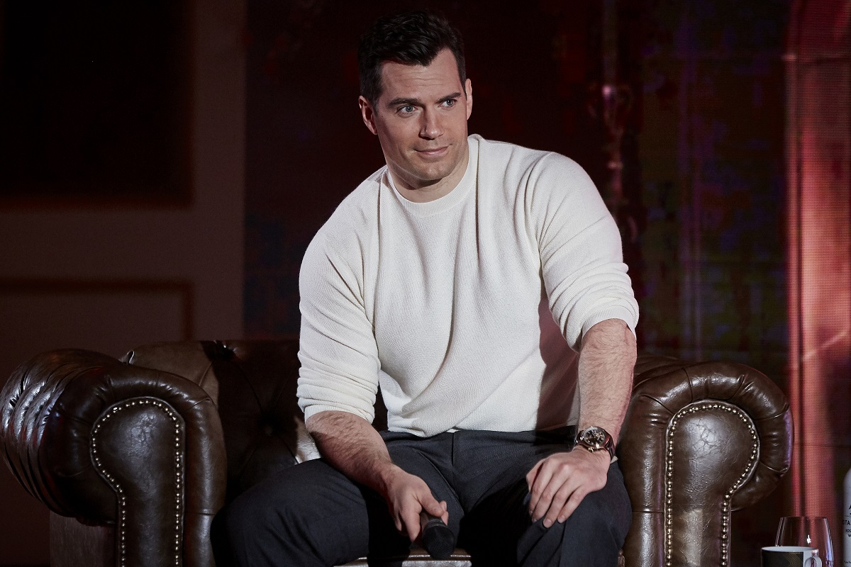 Henry Cavill souriant tout en portant un pull blanc.