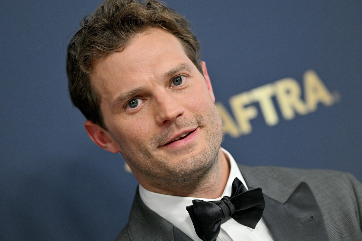 Jamie Dornan porte un costume et sourit