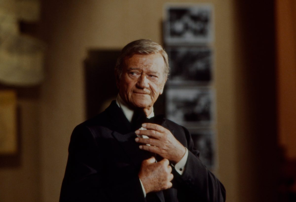 La star de cinéma John Wayne portant un smoking et regardant sur le côté