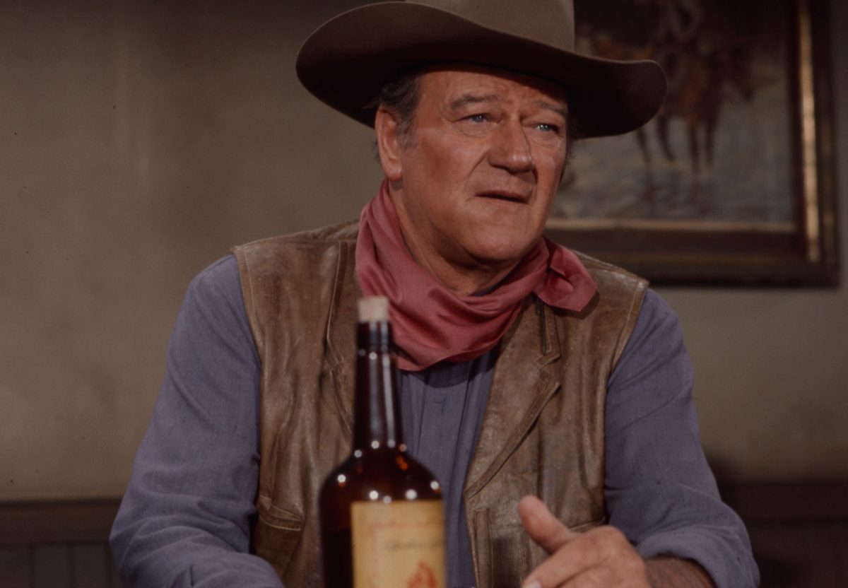 La cible de l'assassinat de Joseph Staline, John Wayne, portant un uniforme de cow-boy devant une bouteille
