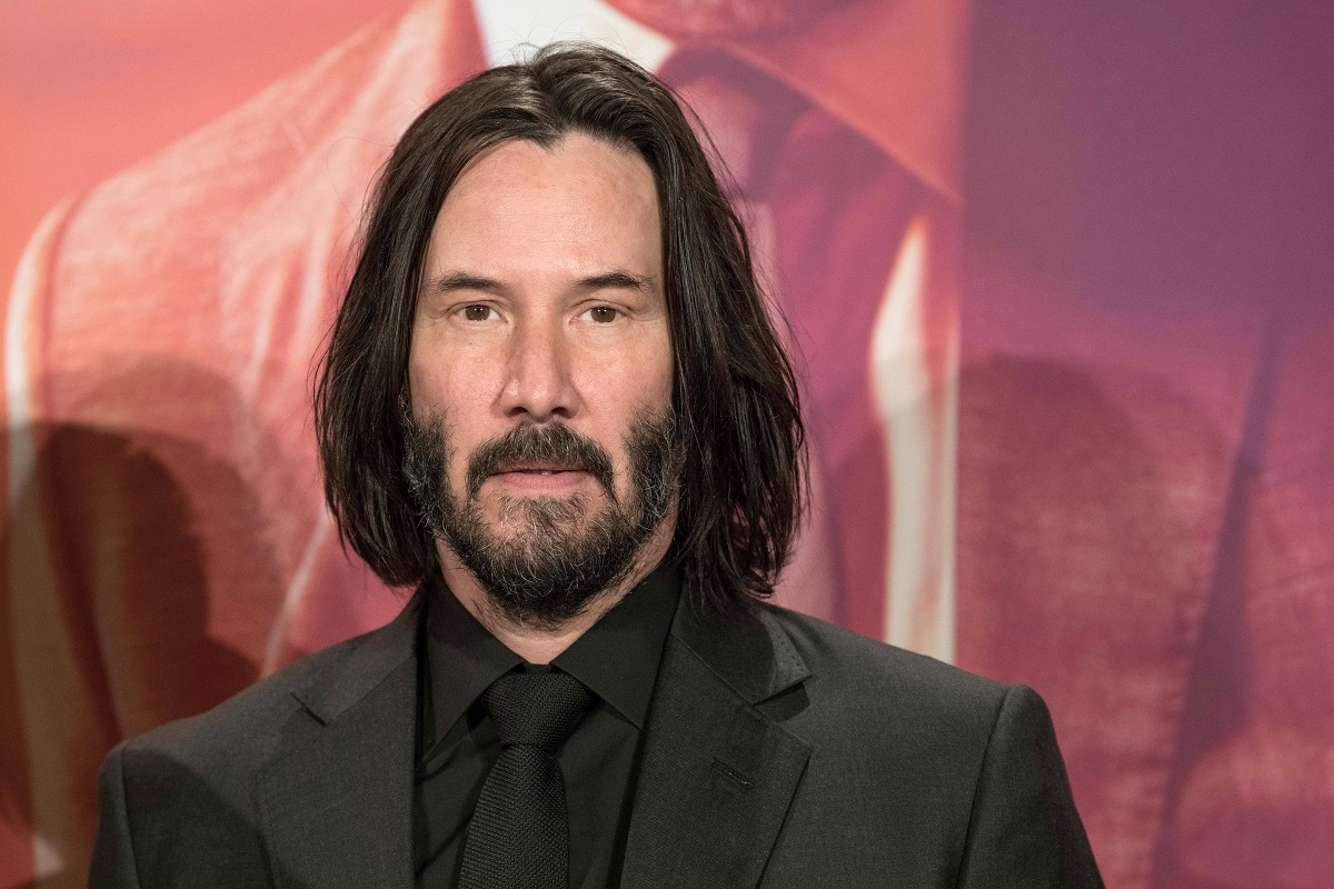 Keanu Reeves posant en portant un costume noir.