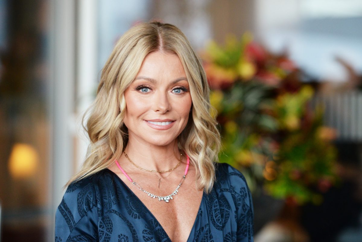 Kelly Ripa portant un haut bleu décolleté et souriant à la caméra