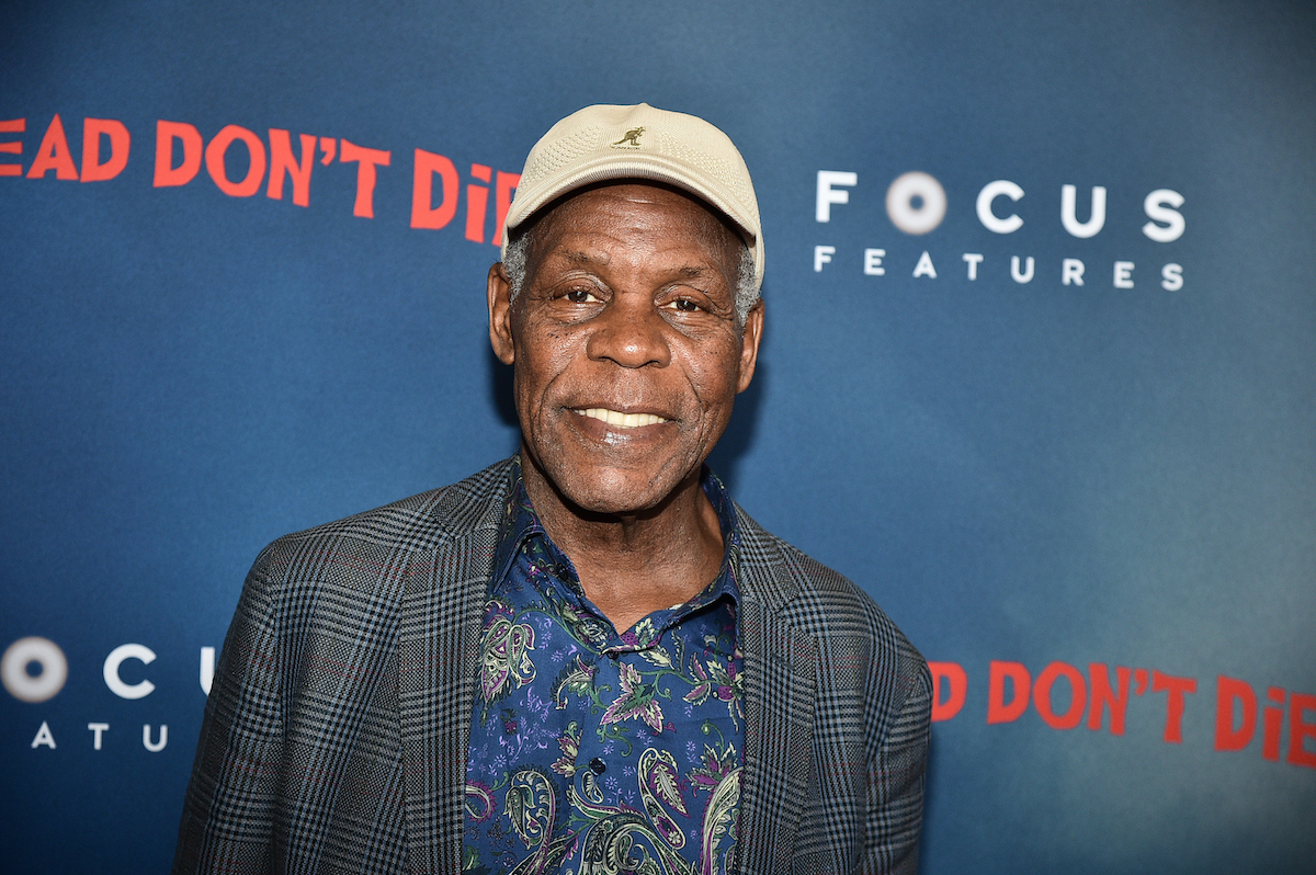 Danny Glover sourit devant les illustrations de 