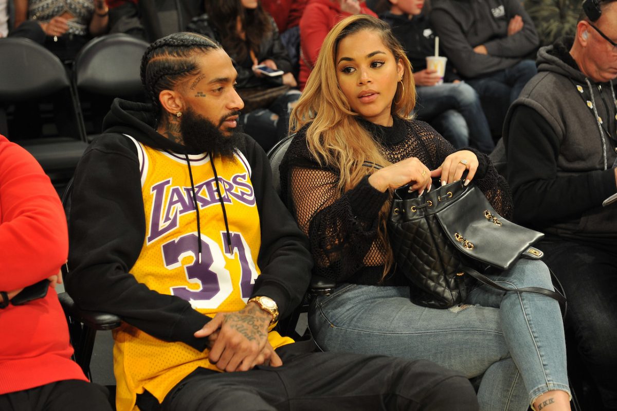 Lauren London et Nipsey Hussle sont assises sur le terrain lors d'un match de basket