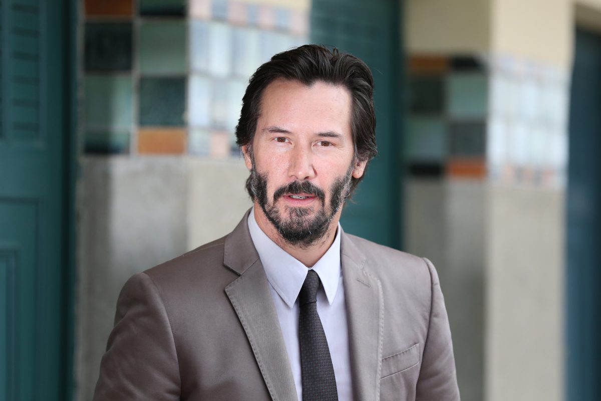 L'acteur de 'The Gift' Keanu Reeves portant un costume devant des piliers carrelés