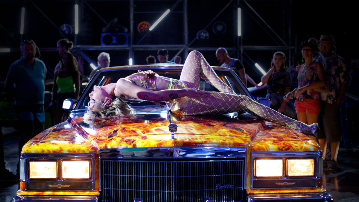 'Titane' Agathe Rousselle comme Alexia sur le capot de la voiture avec des flammes dessus