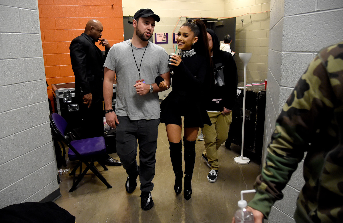 Scooter Braun et Ariana Grande marchent ensemble avec les bras liés.