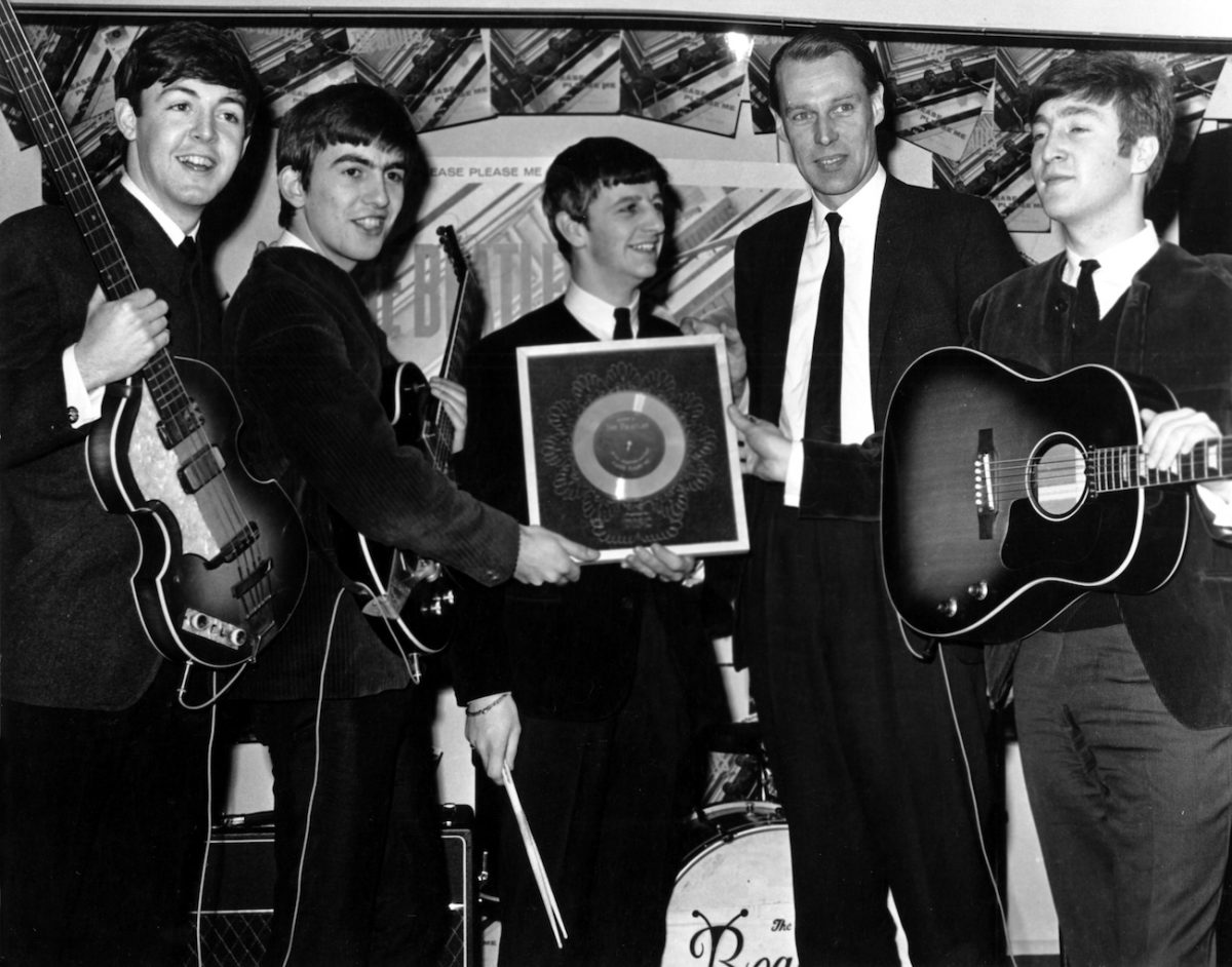 Les Beatles posant en costume avec leur producteur, George Martin, en 1964.