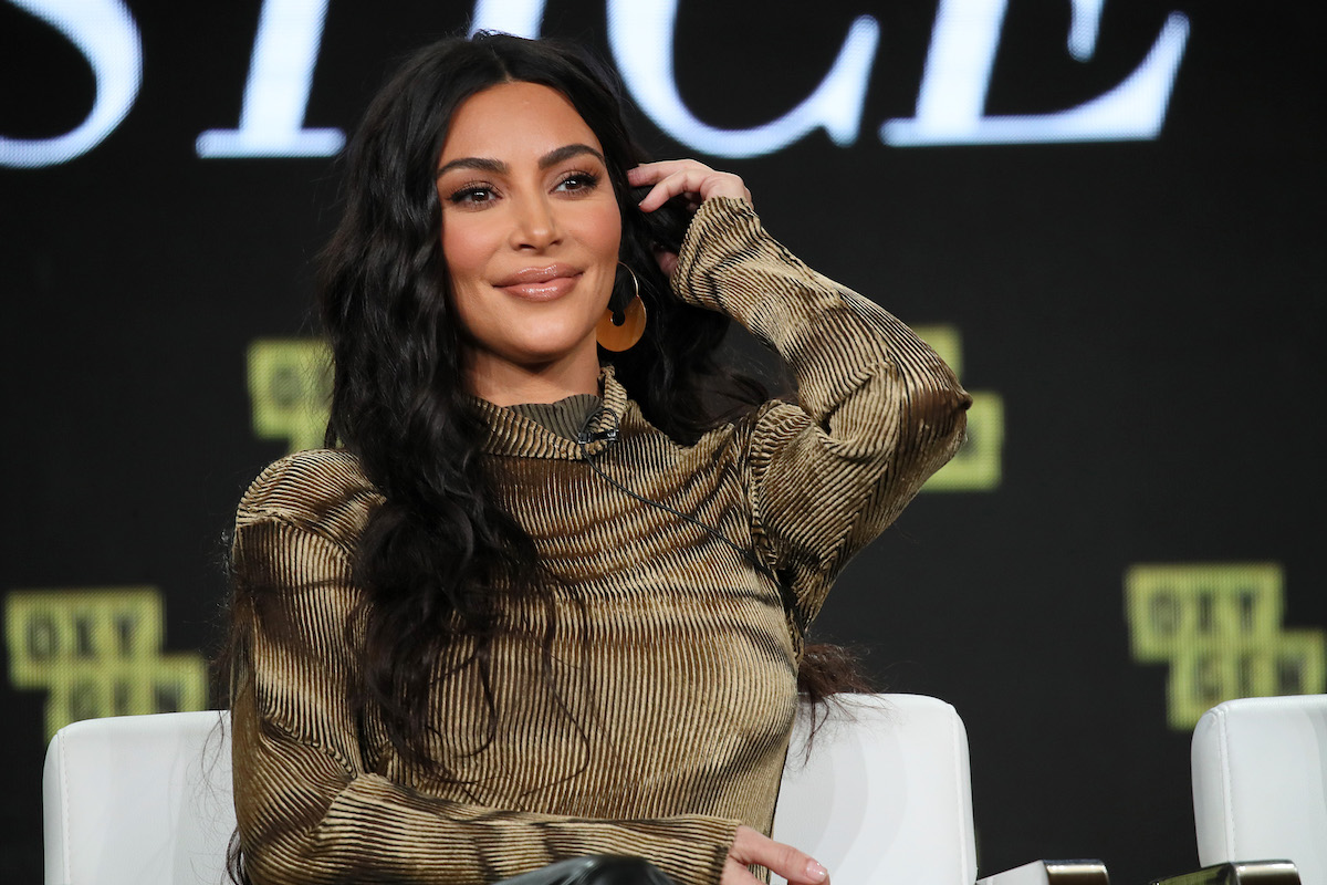 Kim Kardashian sourit et jette ses cheveux sur une épaule.
