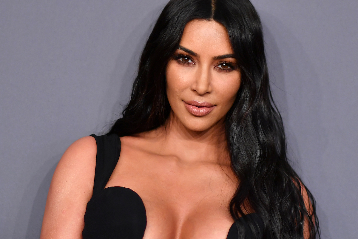 Kim Kardashian pose dans une robe noire lors d'un événement.