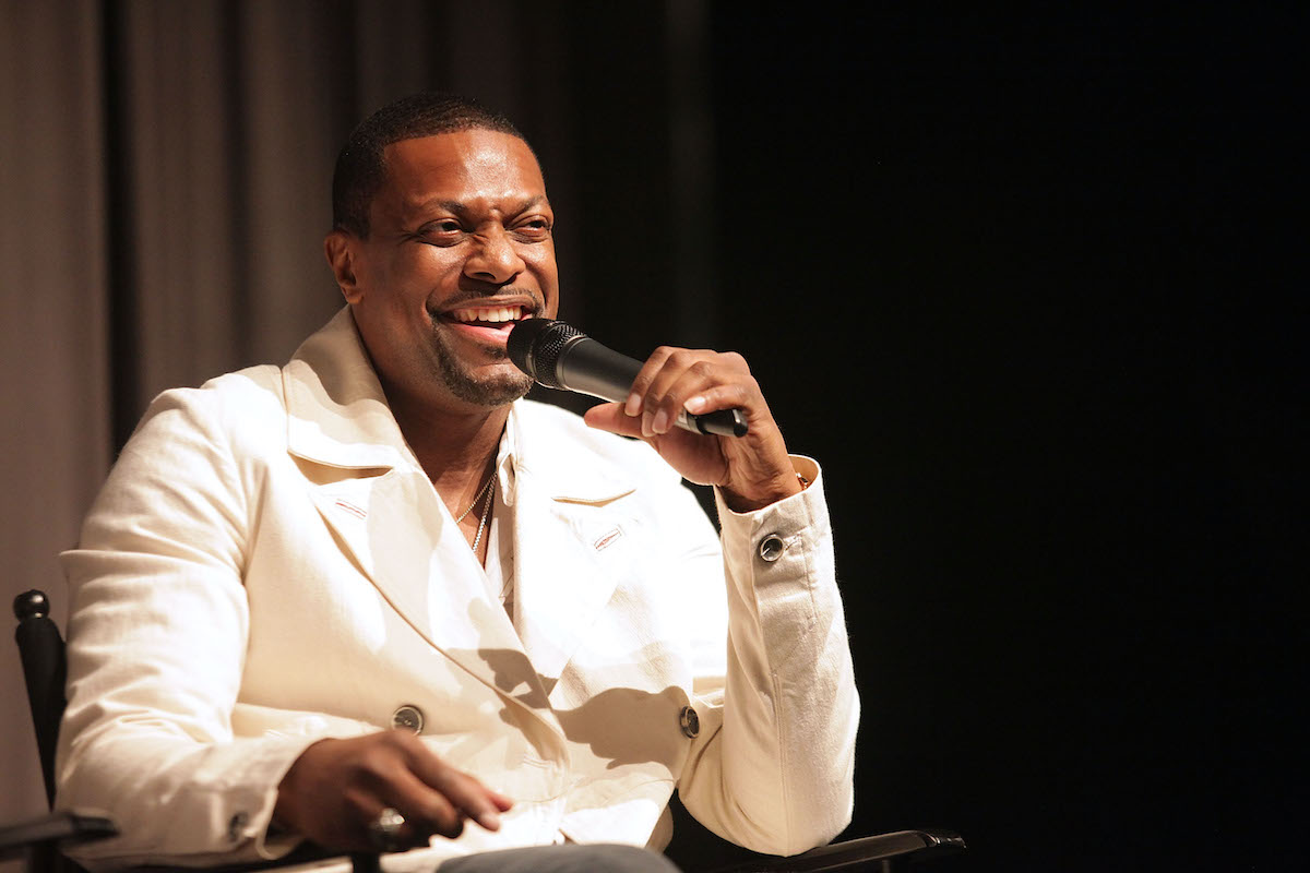 Chris Tucker porte un costume blanc et rit dans le micro
