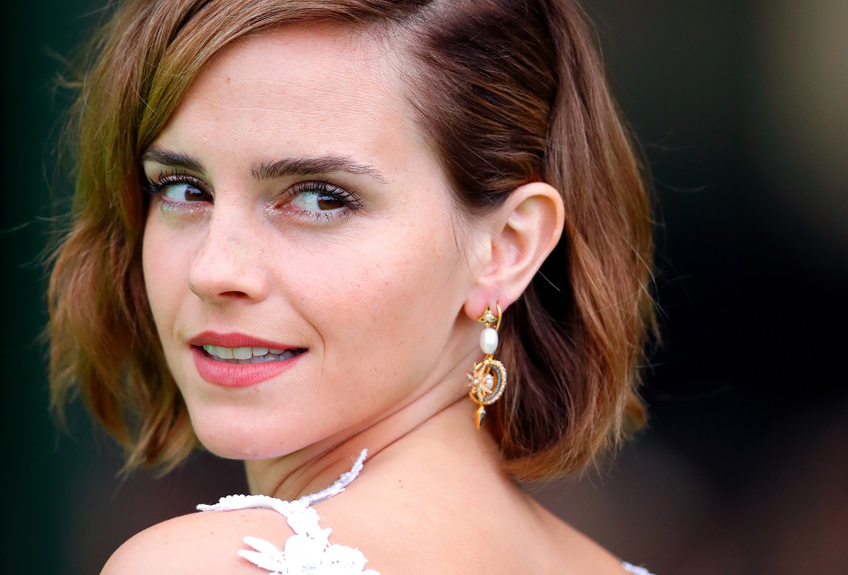 Emma Watson regarde en arrière en souriant.