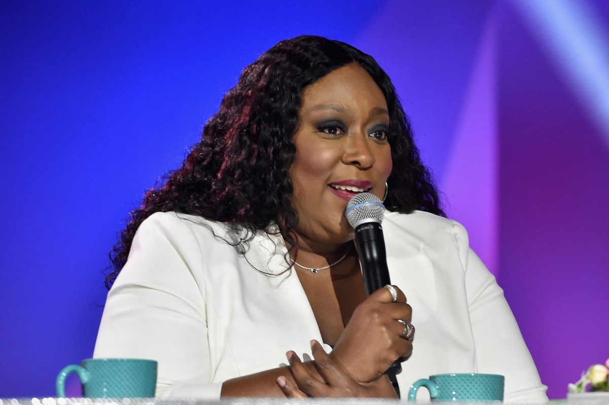 Loni Love tient un micro et porte un blazer blanc