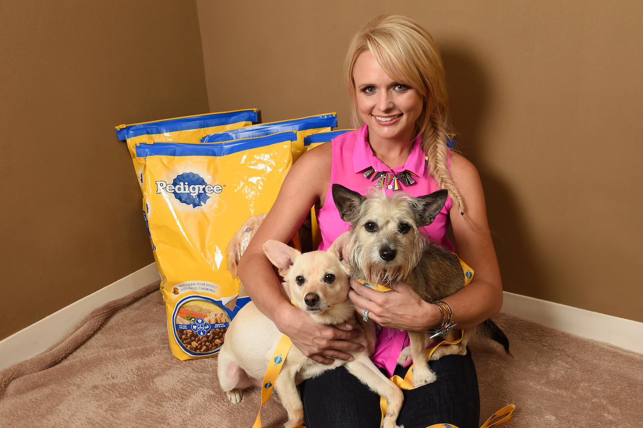 Miranda Lambert sourit en tenant deux petits chiens