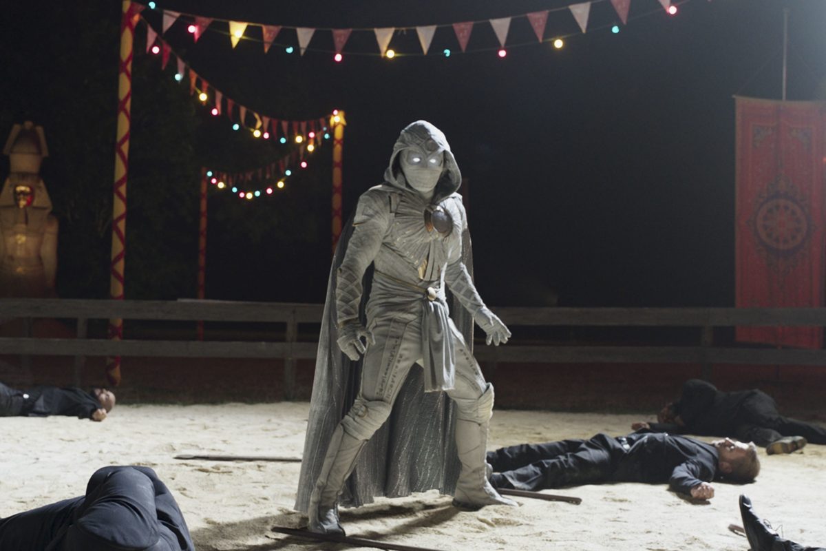 Oscar Isaac, la star de 'Moon Knight', dont la date de sortie est le 30 mars, porte son costume blanc de Moon Knight alors qu'il se tient au-dessus de gars allongés inconscients sur le sol.