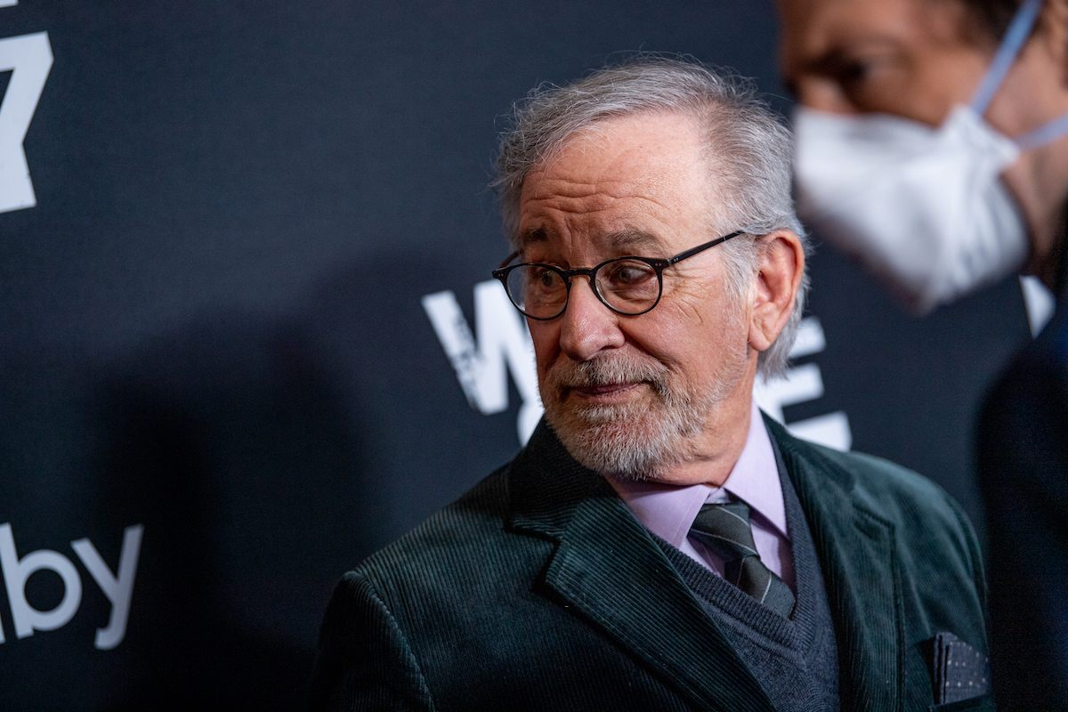 Steven Spielberg regarde à ses côtés tout en portant un costume sur le tapis rouge