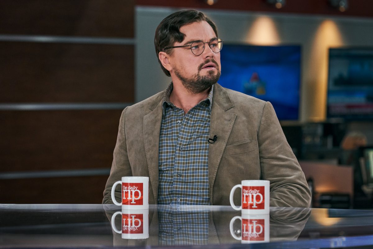 Le nominé du meilleur film aux Oscars 2022 'Don't Look Up' avec Leonardo DiCaprio dans le rôle du Dr Randall Mindy l'air inquiet assis à un bureau de nouvelles avec deux tasses devant lui