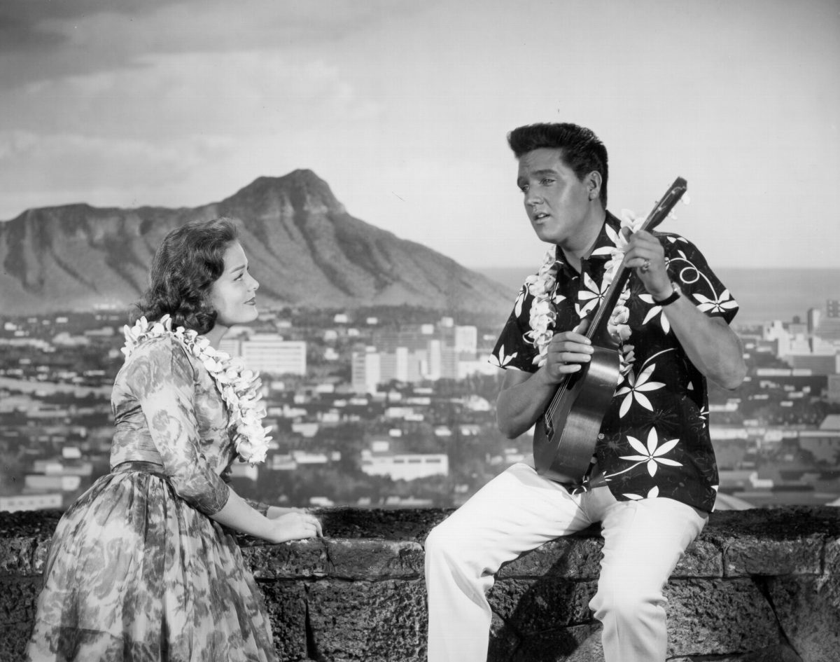 Une femme debout près d'Elvis Presley jouant de la guitare