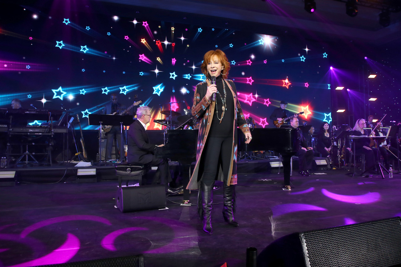 Reba McEntire chante et David Foster joue du piano devant un fond coloré