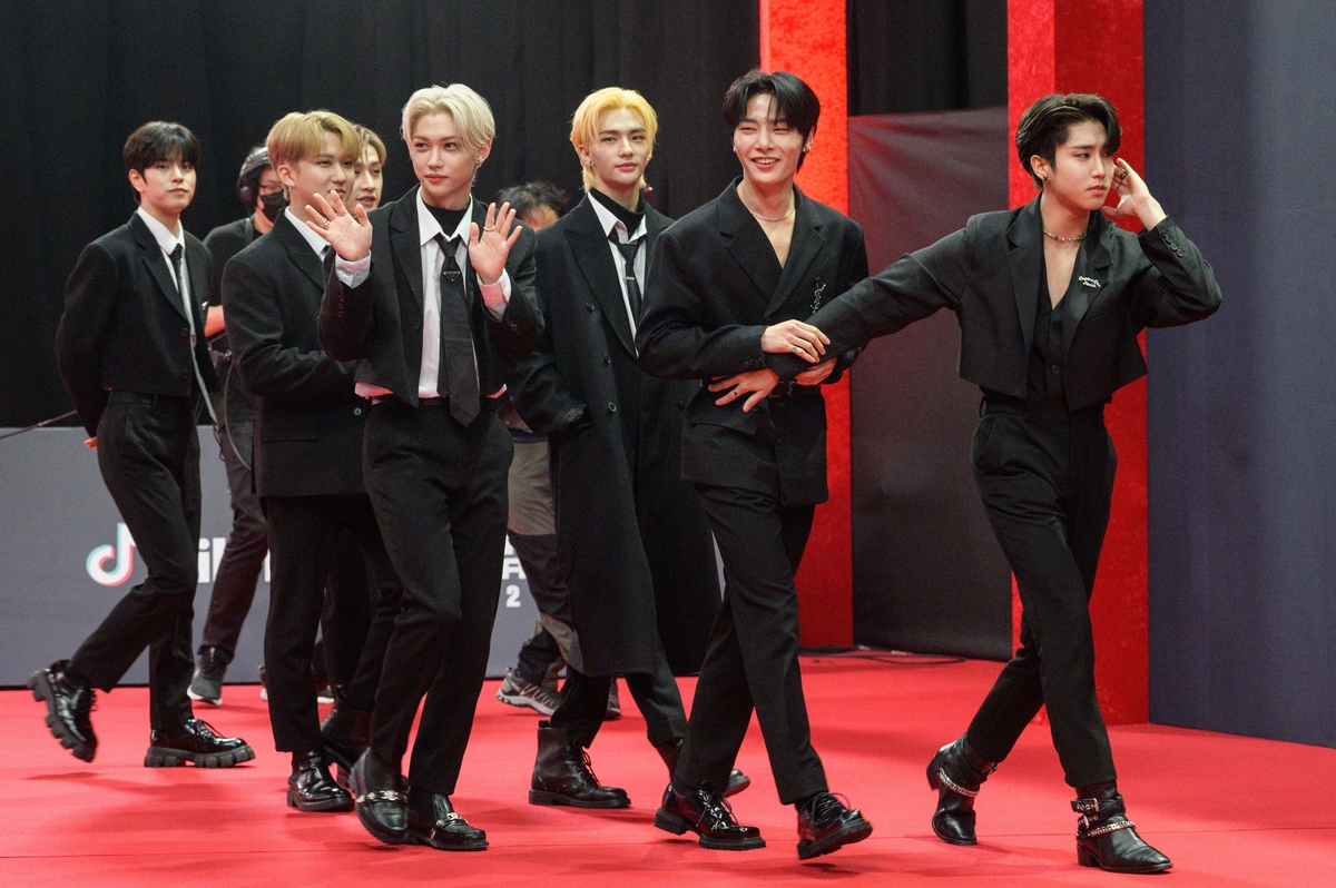 Stray Kids marche sur un tapis rouge en costume noir à Séoul, en Corée.