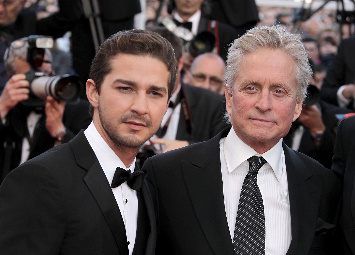 Shia LaBeouf souriant avec Michael Douglas tout en portant un costume.