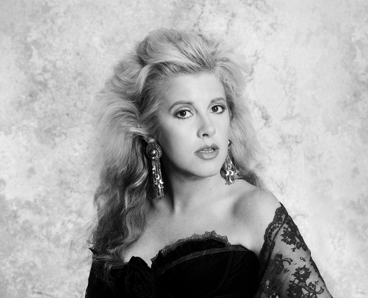 Une photo en noir et blanc de Stevie Nicks portant un haut en dentelle et des boucles d'oreilles pendantes.