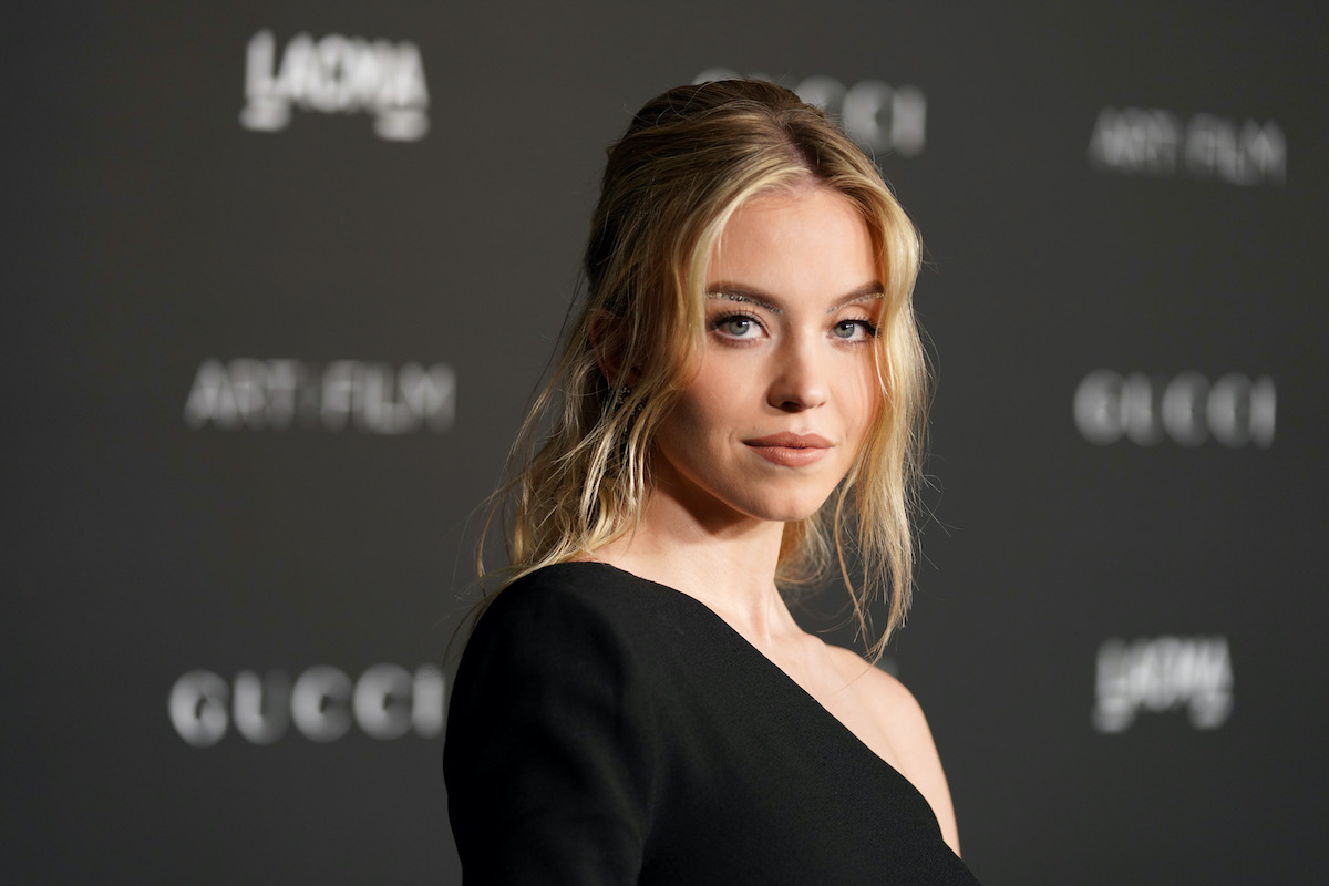 Sydney Sweeney sourit à la caméra dans une robe noire