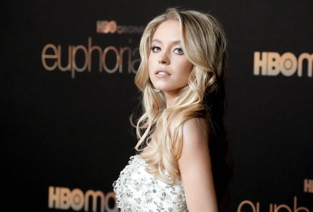Le reconstructeur de voitures Sydney Sweeney dans une robe blanche regardant par-dessus son épaule lors d'un événement