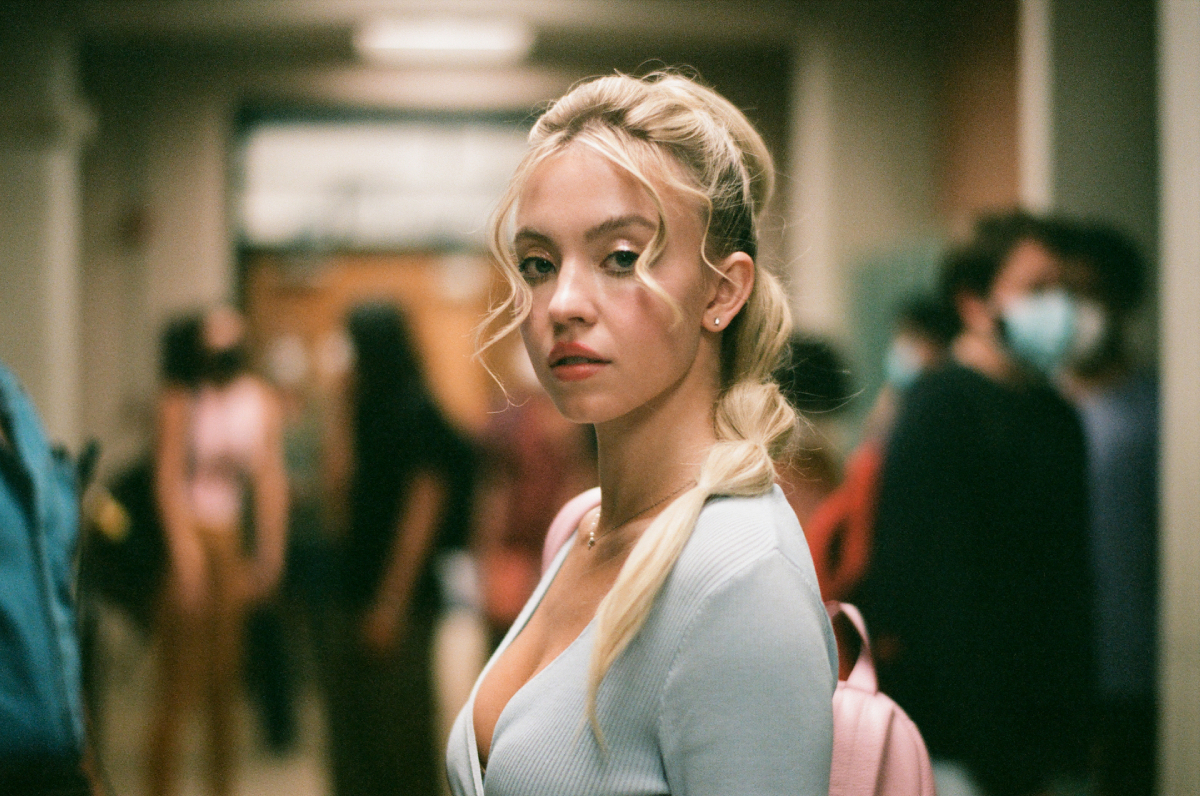 Sydney Sweeney dans le personnage de Cassie dans Euphoria Saison 2. Cassie porte un haut bleu décolleté et ses cheveux sont en queue de cheval.
