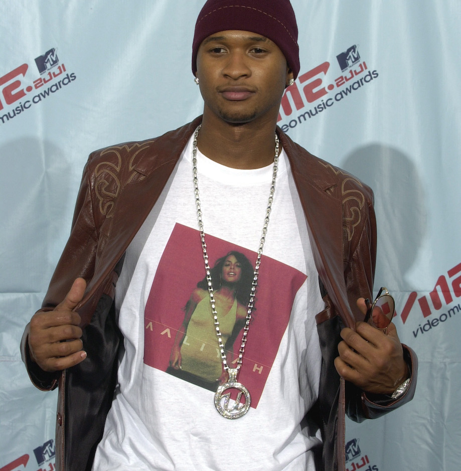 Usher pose pour une photo sur un tapis rouge avec un t-shirt Aaliyah