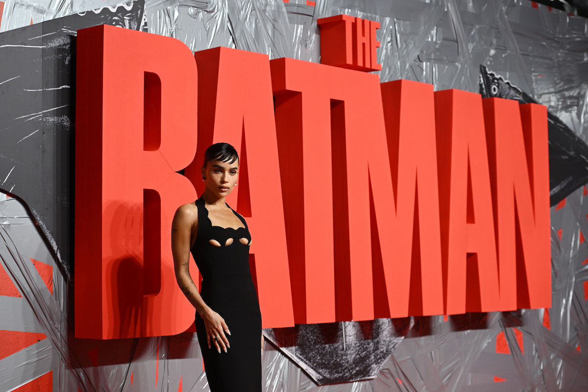 Zoe Kravitz pose devant un grand panneau rouge qui dit "The Batman".