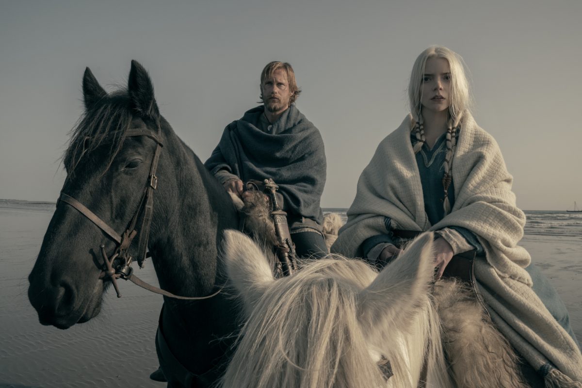 'The Northman' Alexander Skarsgård comme Amleth et Anya Taylor-Joy comme Olga de la forêt de bouleaux assis à cheval avec l'océan en arrière-plan